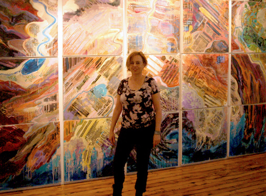 A woman standing in front of a wall with many paintings.