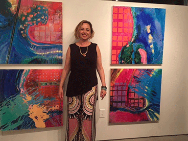 A woman standing in front of four paintings.